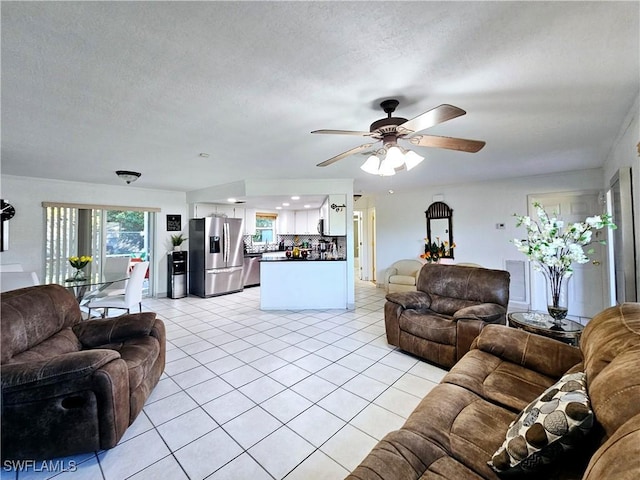 living room with light tile patterned flooring, ceiling fan, and a textured ceiling