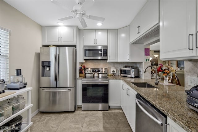 kitchen featuring decorative backsplash, appliances with stainless steel finishes, white cabinets, and dark stone counters