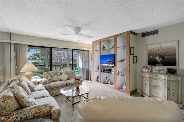 living room with ceiling fan and a textured ceiling