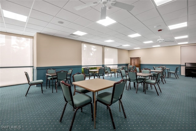 carpeted dining area with a paneled ceiling and ceiling fan