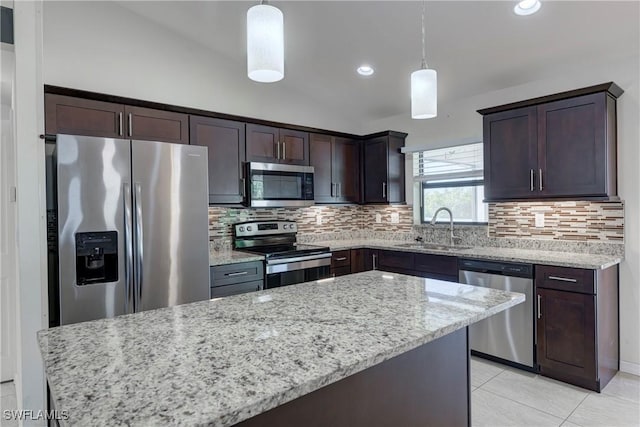 kitchen with appliances with stainless steel finishes, sink, pendant lighting, and light stone counters