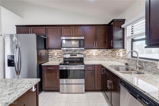 kitchen with sink, stainless steel appliances, tasteful backsplash, light stone countertops, and vaulted ceiling