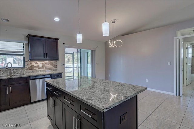 kitchen with light stone counters, sink, stainless steel dishwasher, and a center island