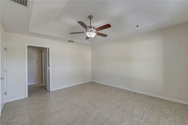 empty room featuring a raised ceiling and ceiling fan