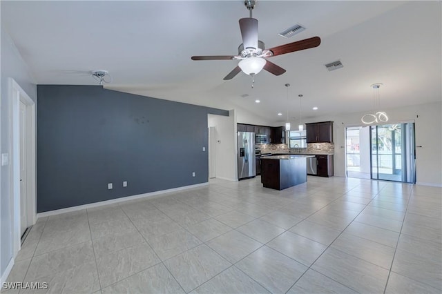 kitchen featuring lofted ceiling, appliances with stainless steel finishes, dark brown cabinetry, a kitchen island, and decorative backsplash