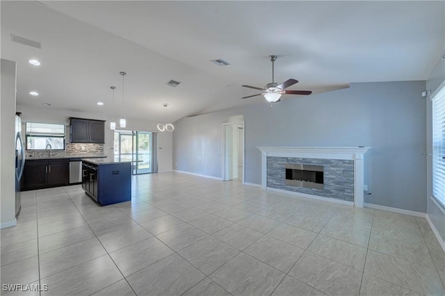 unfurnished living room featuring light tile patterned flooring, lofted ceiling, sink, ceiling fan, and a fireplace