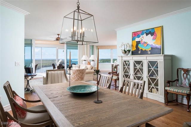 dining space with a water view, ornamental molding, and hardwood / wood-style floors