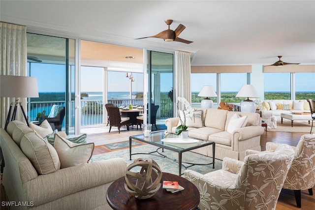 living room with a water view, a wall of windows, ceiling fan, and light hardwood / wood-style flooring