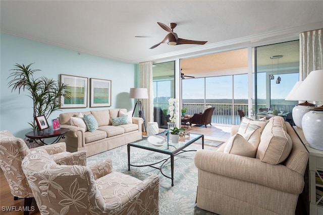 living room featuring light wood-type flooring, crown molding, a wall of windows, and a water view