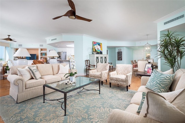 living room with crown molding, light hardwood / wood-style floors, and ceiling fan