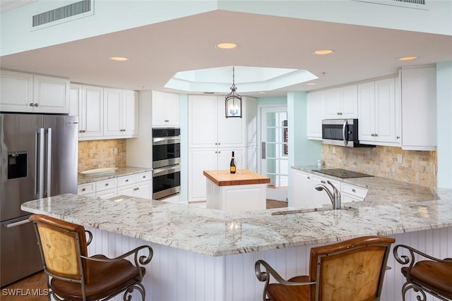 kitchen featuring stainless steel appliances, white cabinetry, a center island, and sink