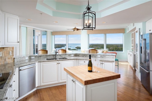 kitchen featuring butcher block countertops, appliances with stainless steel finishes, a water view, a sink, and wood finished floors