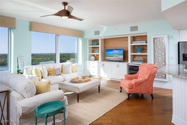 living area featuring wine cooler, visible vents, crown molding, and wood finished floors