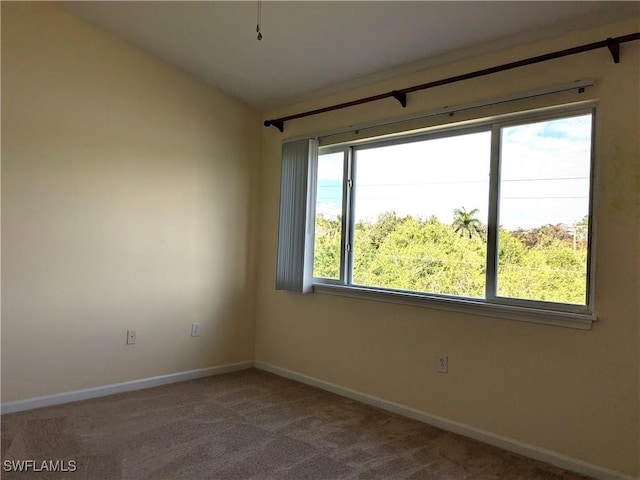 carpeted empty room featuring vaulted ceiling