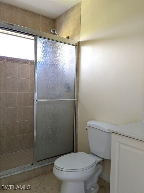 bathroom with toilet, tile patterned floors, and a shower with shower door