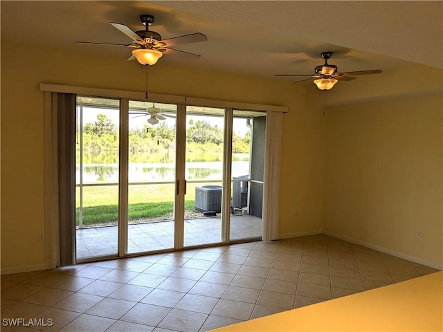 doorway to outside featuring light tile patterned flooring, ceiling fan, and a water view