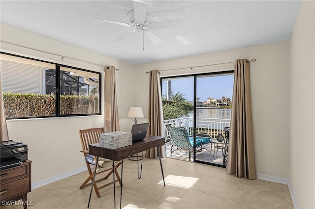 office featuring ceiling fan, light tile patterned floors, a textured ceiling, and a water view