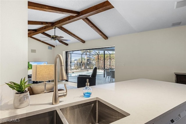 kitchen with ceiling fan, sink, and vaulted ceiling with beams