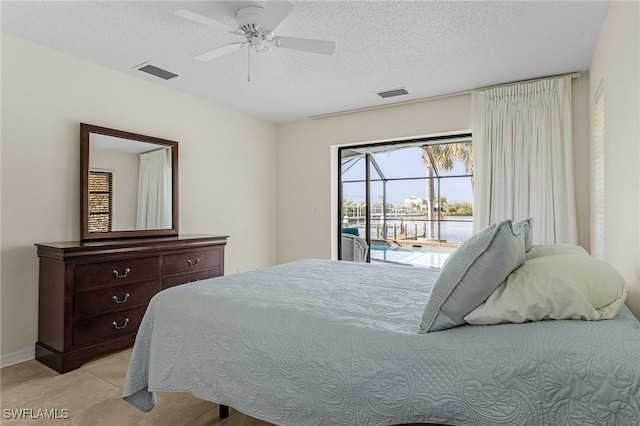 tiled bedroom with ceiling fan, a textured ceiling, and access to outside