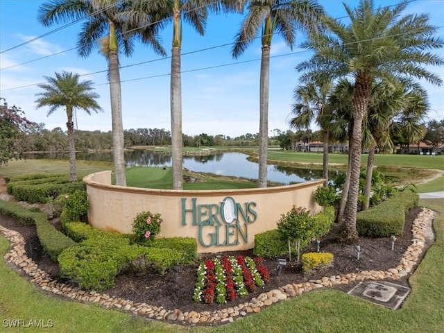 community / neighborhood sign with a water view and a lawn