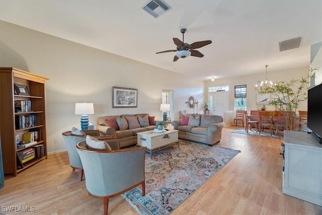 living room featuring ceiling fan with notable chandelier and light wood-type flooring