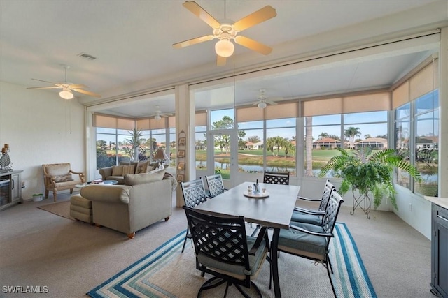 sunroom featuring ceiling fan and a water view