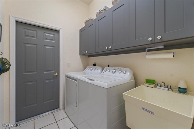 laundry room featuring washer and dryer, sink, light tile patterned floors, and cabinets