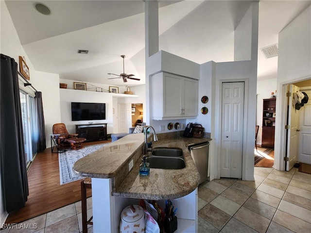 kitchen featuring sink, white cabinetry, a kitchen breakfast bar, stainless steel dishwasher, and kitchen peninsula