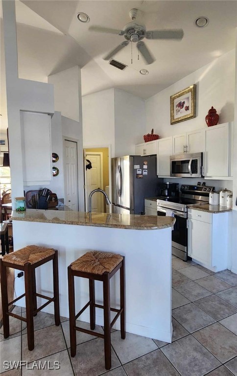 kitchen featuring a breakfast bar, appliances with stainless steel finishes, kitchen peninsula, and white cabinets