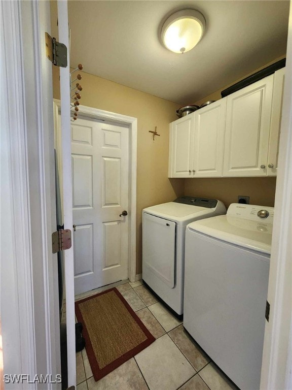 laundry room featuring cabinets, light tile patterned floors, and independent washer and dryer