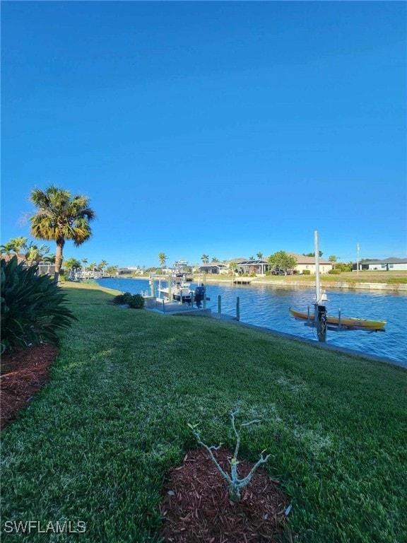 view of dock with a lawn and a water view