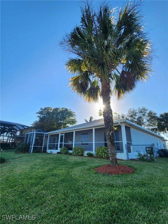 view of front of house featuring a front lawn, a sunroom, and glass enclosure