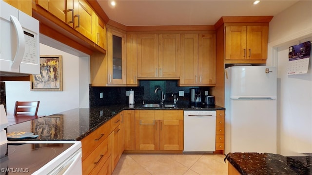 kitchen with light tile patterned flooring, sink, dark stone countertops, decorative backsplash, and white appliances