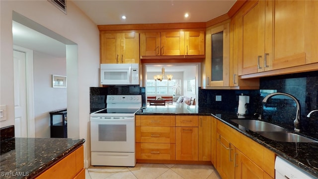 kitchen featuring a notable chandelier, white appliances, sink, and dark stone countertops