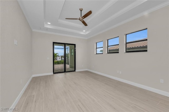 unfurnished room with crown molding, a tray ceiling, light hardwood / wood-style floors, and ceiling fan