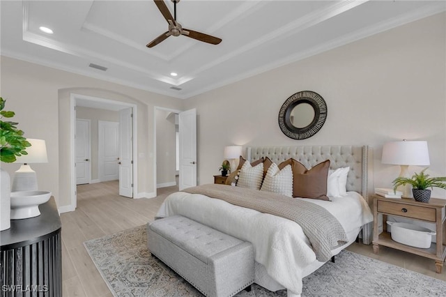 bedroom featuring crown molding, ceiling fan, a tray ceiling, and light hardwood / wood-style floors