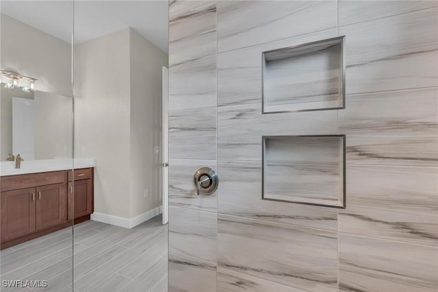 bathroom with tiled shower and vanity