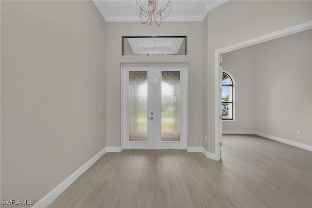 entrance foyer featuring french doors, crown molding, a chandelier, and light hardwood / wood-style flooring