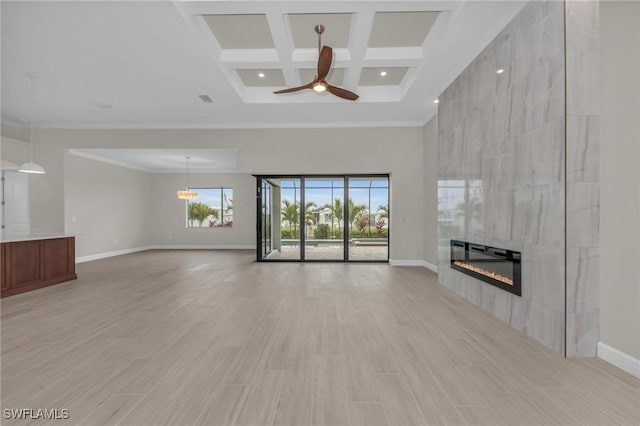 unfurnished living room with light hardwood / wood-style flooring, a tile fireplace, ceiling fan, a high ceiling, and coffered ceiling