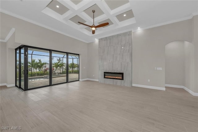 unfurnished living room with coffered ceiling, ceiling fan, a tiled fireplace, light hardwood / wood-style floors, and a high ceiling