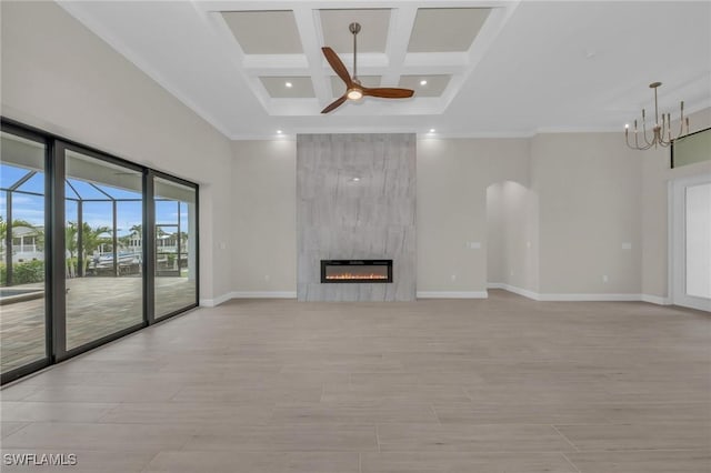 unfurnished living room with a high ceiling, coffered ceiling, a tiled fireplace, ceiling fan with notable chandelier, and light wood-type flooring