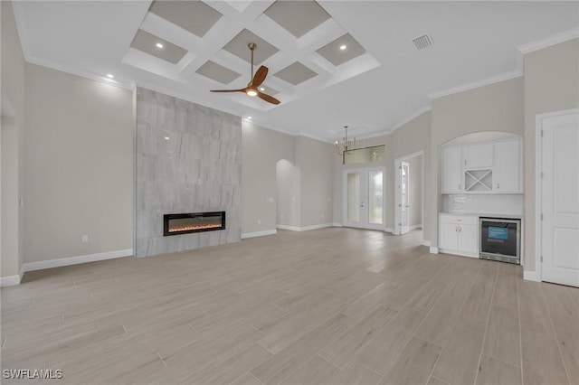 unfurnished living room with coffered ceiling, wine cooler, a fireplace, and light hardwood / wood-style flooring