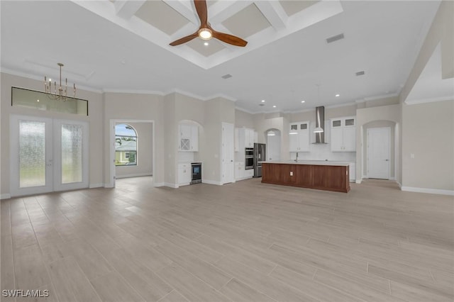 unfurnished living room featuring french doors, beverage cooler, ceiling fan with notable chandelier, and light hardwood / wood-style floors