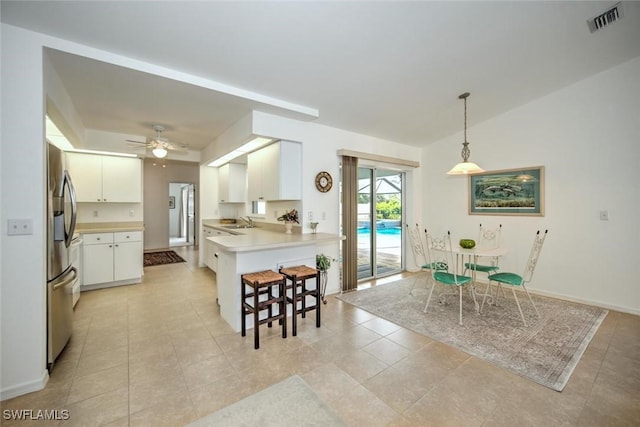 kitchen with stainless steel refrigerator with ice dispenser, sink, decorative light fixtures, kitchen peninsula, and white cabinets