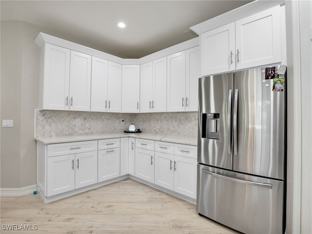 kitchen featuring white cabinets, stainless steel fridge, and backsplash