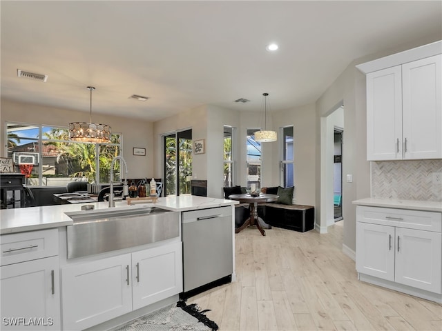 kitchen featuring tasteful backsplash, stainless steel dishwasher, hanging light fixtures, and white cabinets