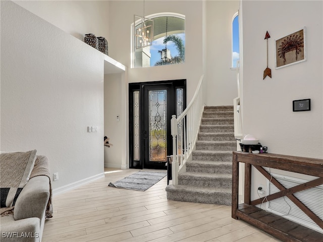 entrance foyer featuring an inviting chandelier, light hardwood / wood-style floors, and a high ceiling