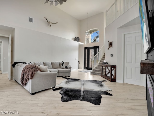 living room with a towering ceiling and light hardwood / wood-style flooring