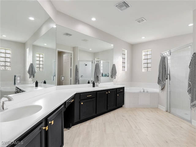 bathroom with vanity, independent shower and bath, and hardwood / wood-style floors