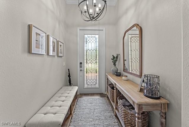 foyer entrance featuring hardwood / wood-style flooring, ornamental molding, and a chandelier